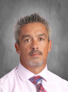 Dr. Daniel McGarry is wearing a collared business shirt and a tie.